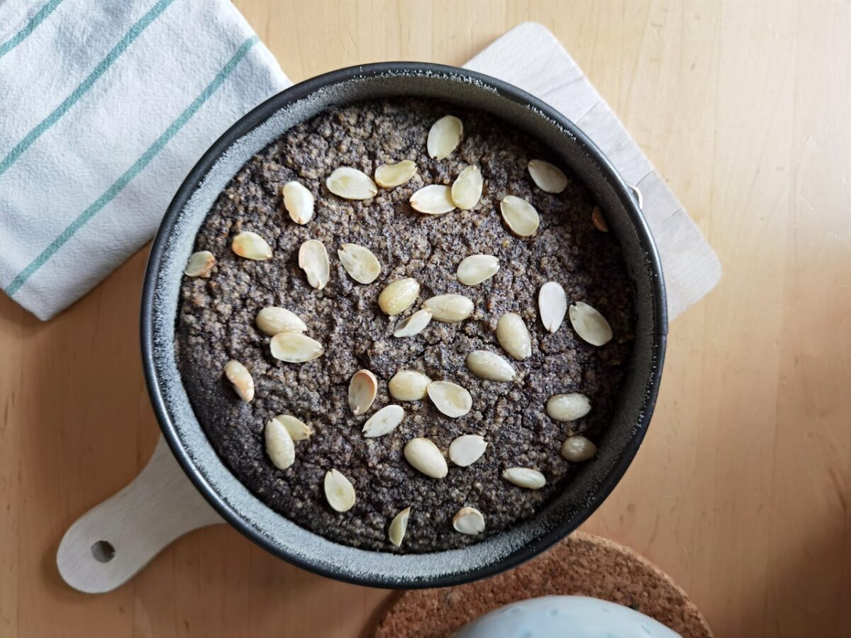 Services Top view of a homemade almond and poppy seed cake in a pan, perfect for dessert enthusiasts.