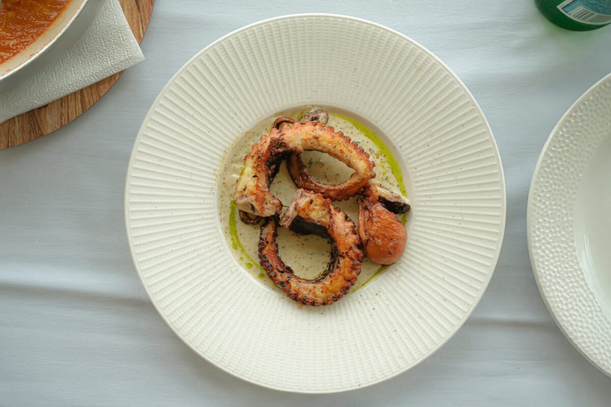 Delicious grilled octopus served elegantly on a textured white plate.